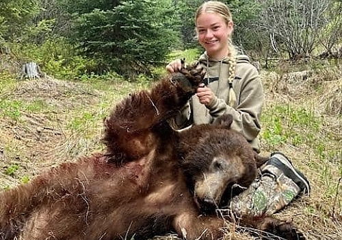  Young girl poses with bear on successful hunting trip